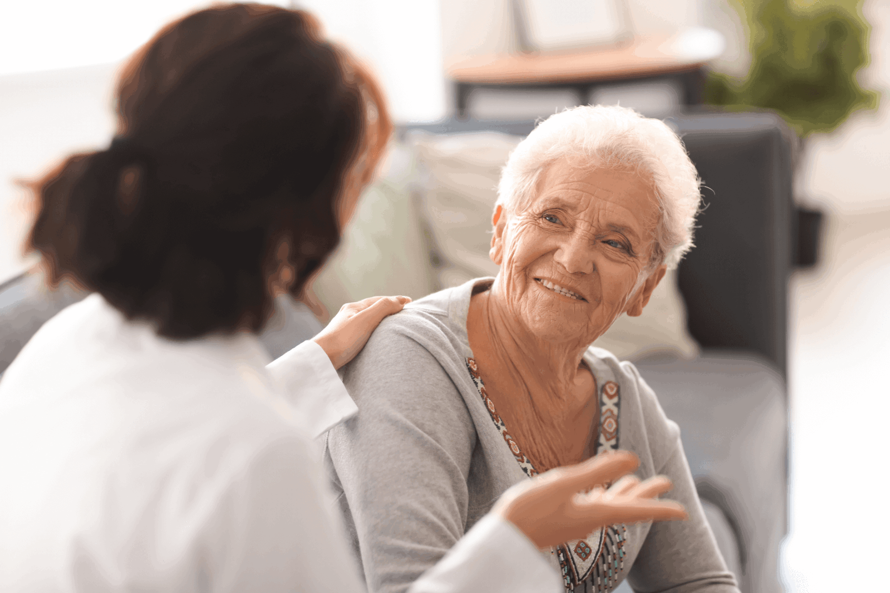 Older adult, smiling, having a conversation with a healthcare provider.